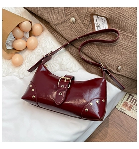 Vue détaillée du sac à bandoulière en cuir verni bordeaux avec rivets et boucle vintage
