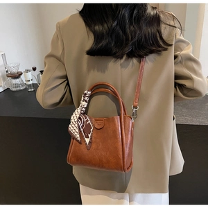 Detail of vintage brown tote bag with decorative silk scarf handle and leather texture