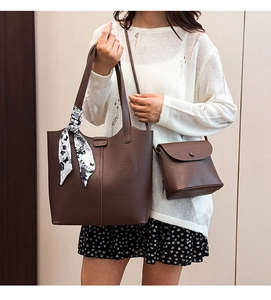 Detail of dark brown lychee leather tote bag with a floral scarf on handle and crossbody pouch