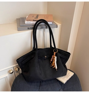 Detail of black suede tote bag with metal buckle strap and colorful wooden bead charm