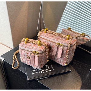 Detail of pink tweed crossbody bags with gold chain straps and floral metal logo charms