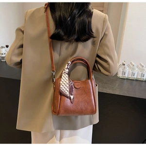 Detail of vintage brown leather handbag with geometric print silk scarf on handle