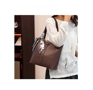 Detail of dark brown pebble leather tote bag with elegant silk scarf on handle