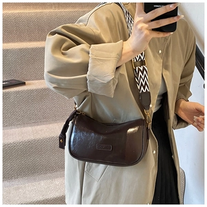 Detailed macro view of dark brown semi-circle bag with wave pattern shoulder strap