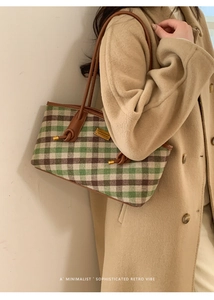 Détail du sac cabas à carreaux avec poignée en cuir marron et emblème doré