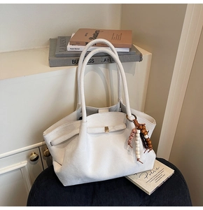 Detail of white suede tote bag with decorative wooden beads and tassel accessory