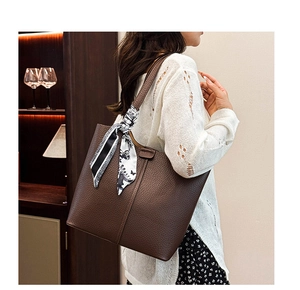 Detail of a brown lychee pattern tote bag with decorative silk scarf on the handle