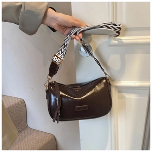 Detail of dark brown glossy Boston bag with geometric wide strap and tassel zipper pull