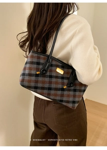 Détail d'un sac cabas rétro à carreaux avec logo doré et lanière en cuir sur modèle