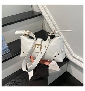 Détail du sac bandoulière en cuir blanc brillant avec rivets dorés et boucle métal