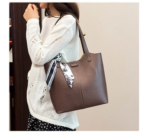 Brown leather tote bag with lychee texture and decorative scarf on a model's shoulder