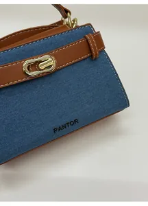 Close-up of contrast denim and brown leather on Kelly bag with gold metal buckle