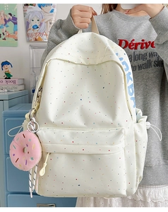 Detail view of canvas backpack with colorful star patterns and pink donut plush charm