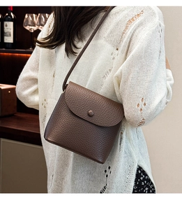 Lifestyle shot of woman wearing dark brown lychee leather bucket bag in cozy wine cellar