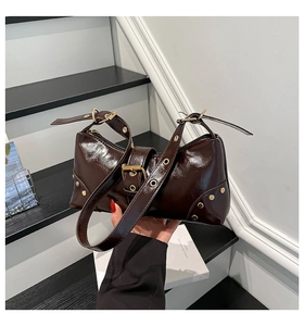 Détail du sac bandoulière en cuir marron chocolat brillant avec œillets et rivets
