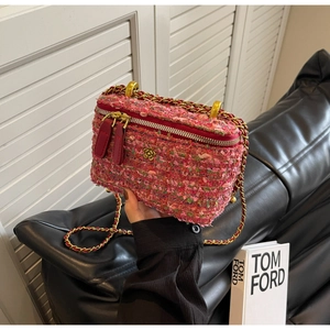Close-up of pink tweed mini box bag with gold flower logo and interwoven chain strap