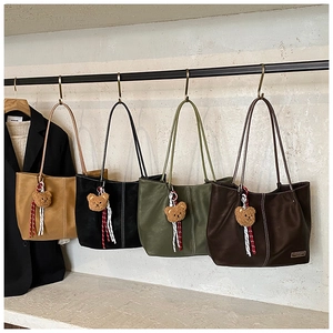 Detail of matte leather tote bags in four colors with bear charms and white stitching