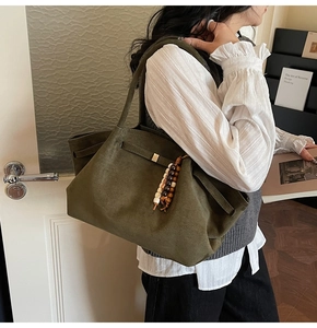 Detail of dark green tote bag in suede texture with wooden bead vintage charm