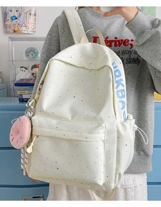 Detail of white canvas backpack with colorful polka dots and pink donut plush charm