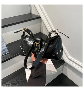 Détail du sac en cuir brillant noir montrant les rivets dorés et boucles métalliques