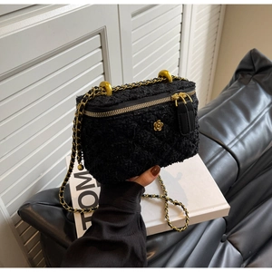 Detail of black tweed mini bag with golden flower logo and elegant leather chain strap