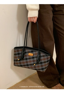 Détail d'un sac cabas à carreaux vintage avec lanières en cuir et emblème doré élégant