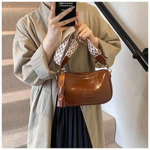 Close-up of brown polished leather crossbody bag with ethnic patterned wide strap