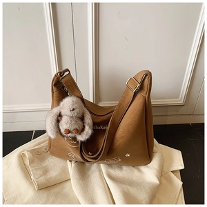 Detalle del bolso de cuero marrón con diseño de gato y colgante de conejo