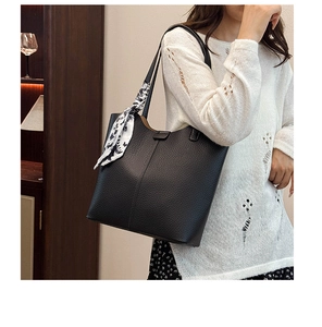 Detail of black lychee grain leather tote bag with printed silk scarf on handle