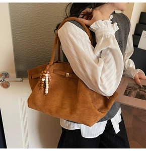 Detail of vintage brown suede tote bag with bohemian wooden bead charm and metal ring
