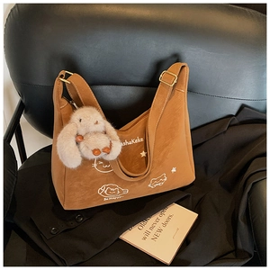 Detalle de un bolso tote de ante marrón con ilustración de gato y colgante de conejo