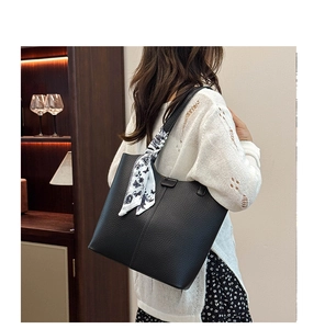 Large black litchi grain leather tote bag with a floral scarf on a shoulder strap
