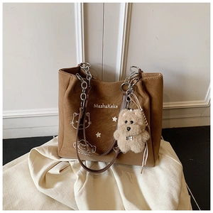 Dettaglio borsa tote in pelle marrone con gatto illustrato, catena e ciondolo orsetto plush