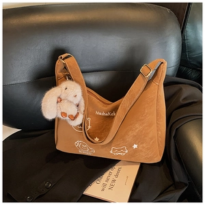 Detalle del bolso hobo de ante marrón con bordado de gato y amuleto de conejo