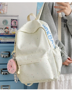 Detail of white printed backpack showing side storage, woven strap and donut plush pendant
