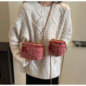 Detail of pink tweed shoulder bag set with gold flower logo and metal chain strap