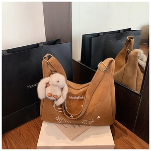 Detalle del bolso tote de cuero marrón con estampados MashaKeke y colgante de conejo