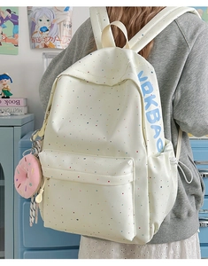 Side view of white casual backpack with colorful dots and pink doughnut pendant charm