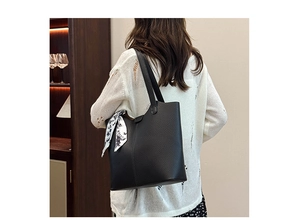 Black pebbled leather tote bag with floral silk scarf detail shown on a shoulder