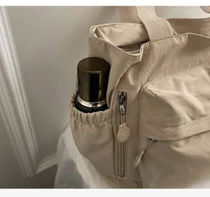 Detail der beigen Nylon-Tragetasche mit elastischer Seitentasche und Reißverschlussfach