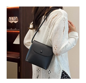 Close-up of black lychee grain leather texture on a minimalist flap crossbody bag