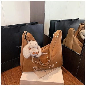 Detalle de bolso hobo de ante marrón con estampados de dibujos y colgante de conejo