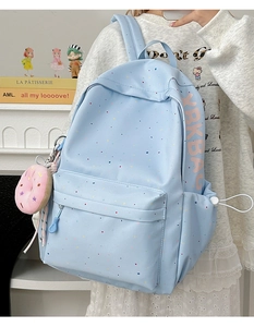 Detail of light blue polka dot backpack with XKBAG logo and plush donut charm