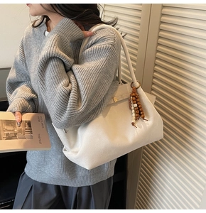 Detailed texture of white suede tote bag with decorative wooden beads on a model