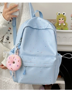 Detail of light blue polka dot backpack featuring a pink donut plush pendant accessory