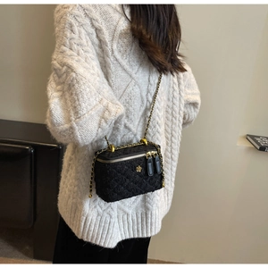 Detail of black quilted tweed crossbody bag with golden flower logo and chain strap