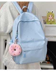 Detailed back view of a light blue student backpack with colorful dots and a donut charm