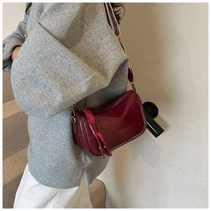 Detail of dark red vintage pillow bag with woven shoulder strap and logo embossing