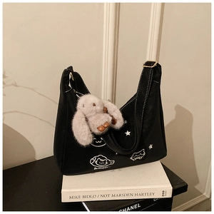 Detalle de bolso bandolera negro con bordado de gato y colgante de conejo de peluche