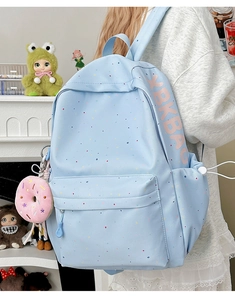 Detail view of light blue canvas backpack with colorful print and pink donut keychain